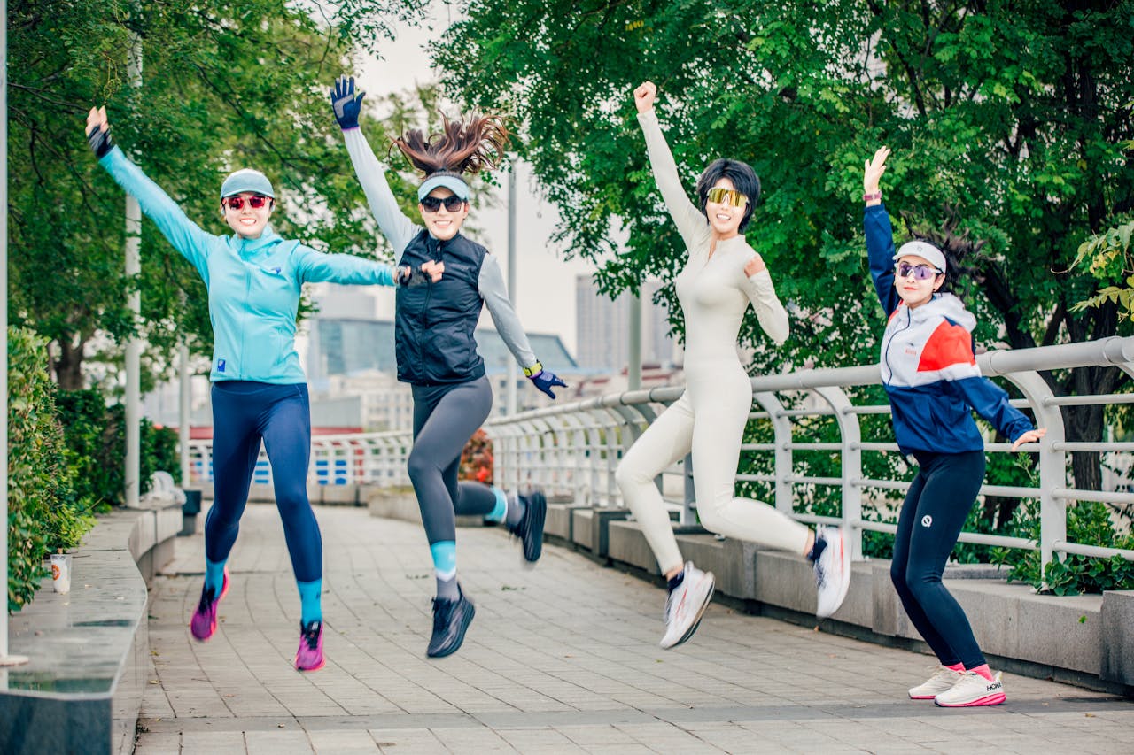 Group of women energetically jumping outdoors, enjoying fitness under sunny skies.