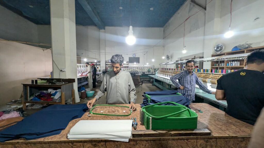 Operators loading garments into embroidery hoops at Ravix Pro Industry clothing factory in Daska, Sialkot, Pakistan