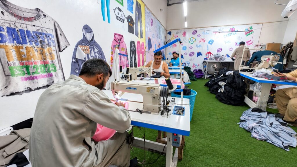 Operator stitching a garment on an industrial sewing machine at Ravix Pro Industry clothing factory in Daska, Sialkot, Pakistan