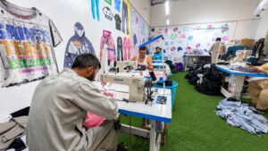 Operator stitching a garment on an industrial sewing machine at Ravix Pro Industry clothing factory in Daska, Sialkot, Pakistan